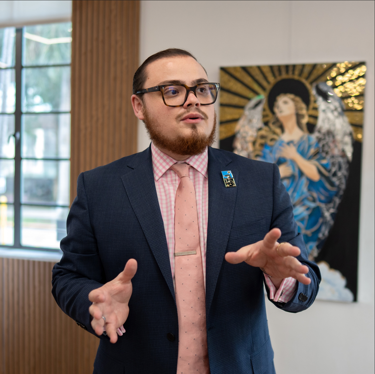 Cesar Evander speaking with a painting in the background