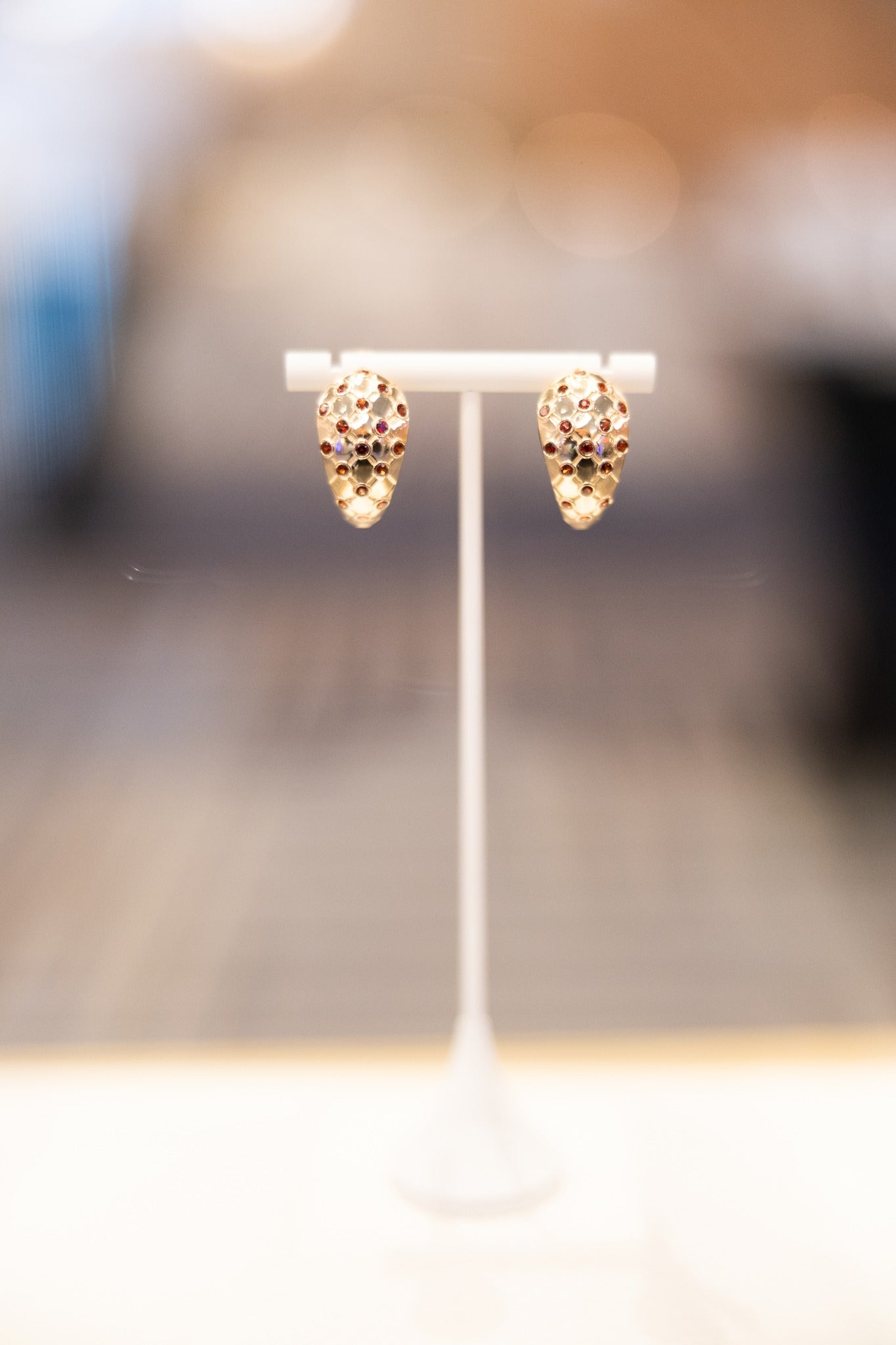Lattice earrings on a white stand with a blurred background