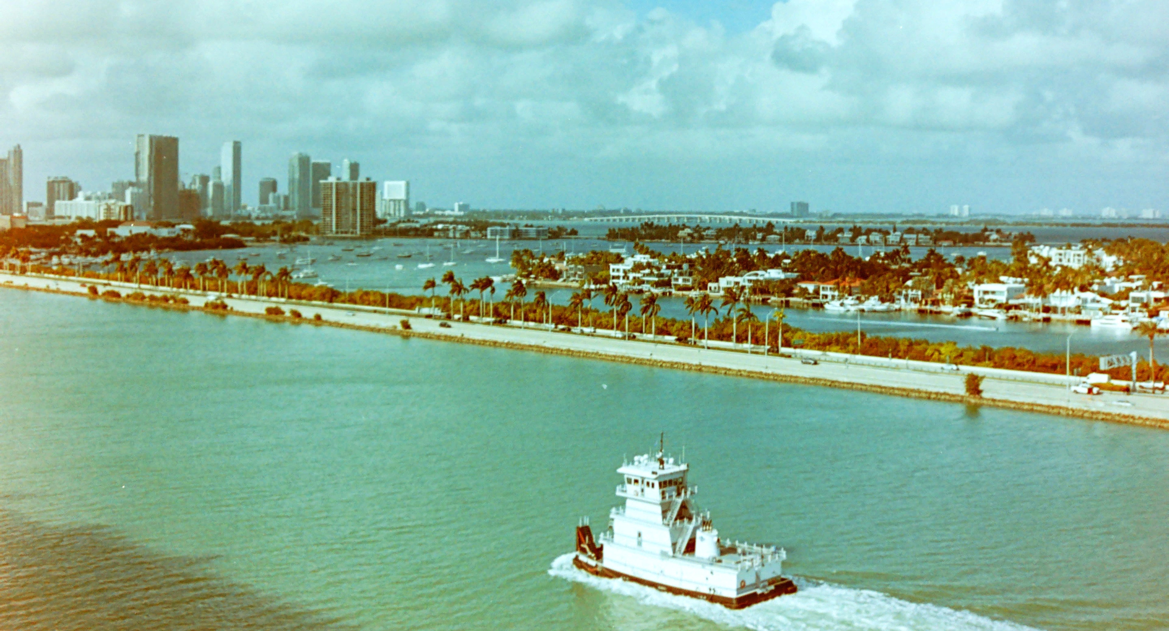 City skyline with a boat on a body of water under a cloudy sky