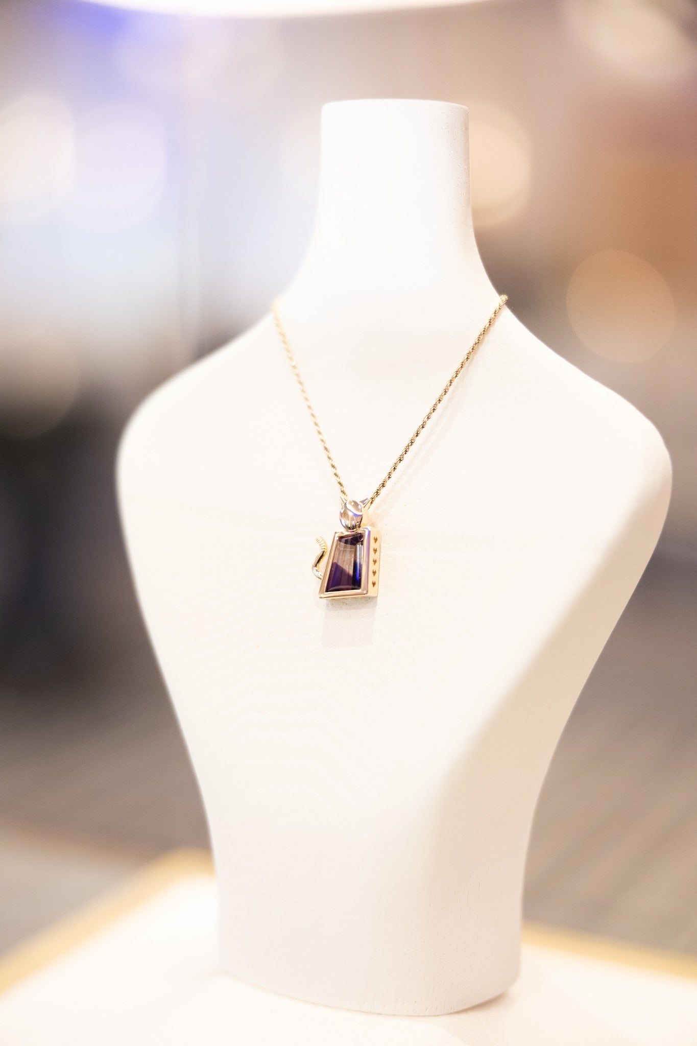 Purrever pendant on a white mannequin bust against a blurred background
